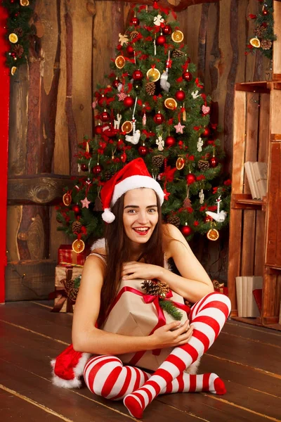 Gelukkig jongedame in rode kerstmuts en rode jurk in de buurt van Nieuwjaar t — Stockfoto