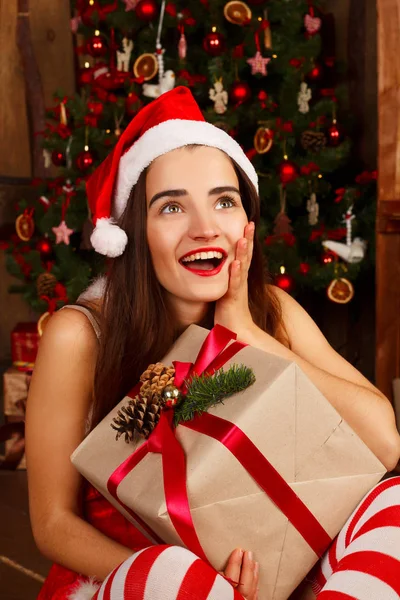 Giovane donna felice in cappello rosso di Babbo Natale e vestito rosso vicino al nuovo anno t — Foto Stock