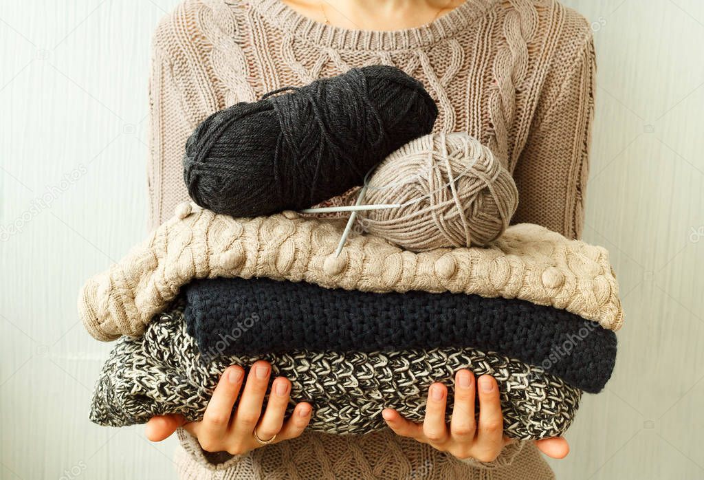Picture of cozy knitted woolen sweaters in woman's hands