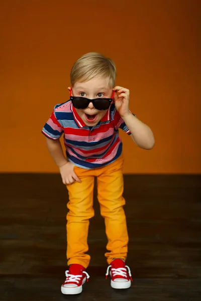 Portrait of little boy in yellow jeans with sunglasses over yell — Stock Photo, Image