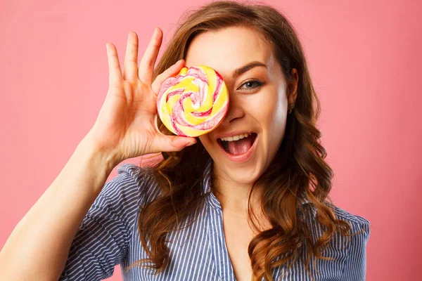 Porträtt av en glad söt flicka hålla sött godis över rosa ba — Stockfoto