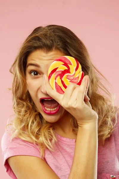 Retrato de una linda chica feliz sosteniendo dulces sobre ba rosa — Foto de Stock