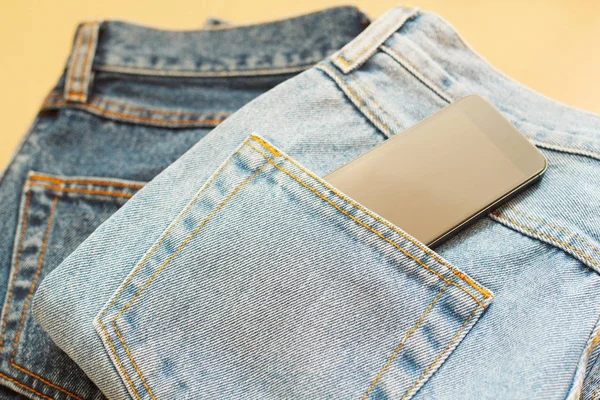 Bild von zwei Jeans mit Handy in der Tasche auf Holzrücken — Stockfoto