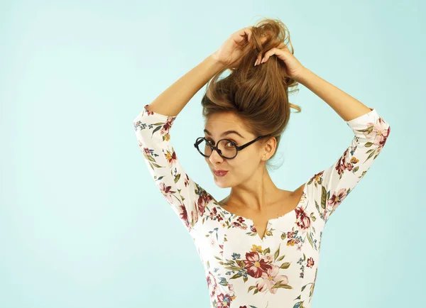 Lustige hübsche junge Frau mit runder Brille, die ihre Haare hochhält — Stockfoto