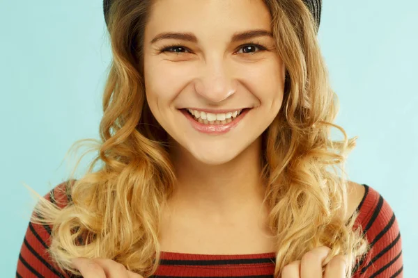 Schöne junge glückliche Frau lächelt im Studio über blauem Hintergrund — Stockfoto