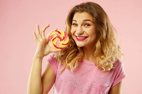 Porträt eines glücklichen Mädchens, das süße Bonbons über rosa Hintergrund hält — Stockfoto