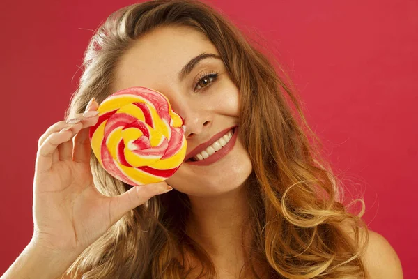Porträtt av en glad söt flicka hålla sött godis över röda bac — Stockfoto