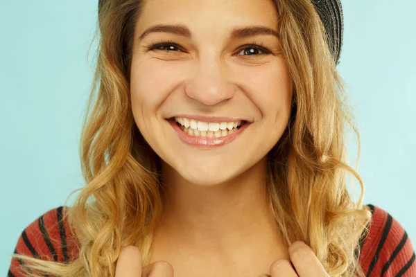 Schöne junge glückliche Frau lächelt im Studio über blauem Hintergrund — Stockfoto
