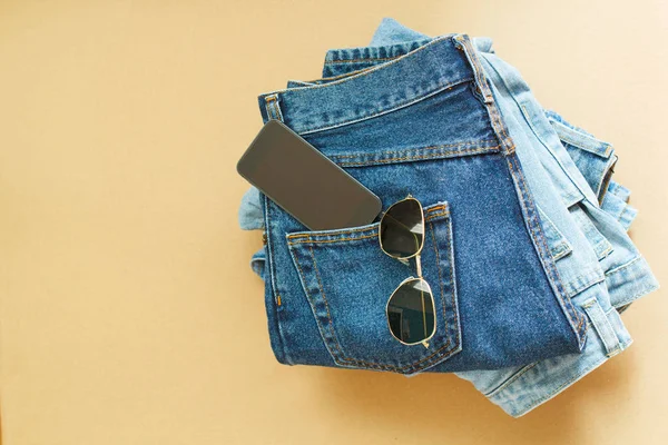 Bild von zwei Jeans mit Handy in der Tasche und Brille auf Handwerk — Stockfoto