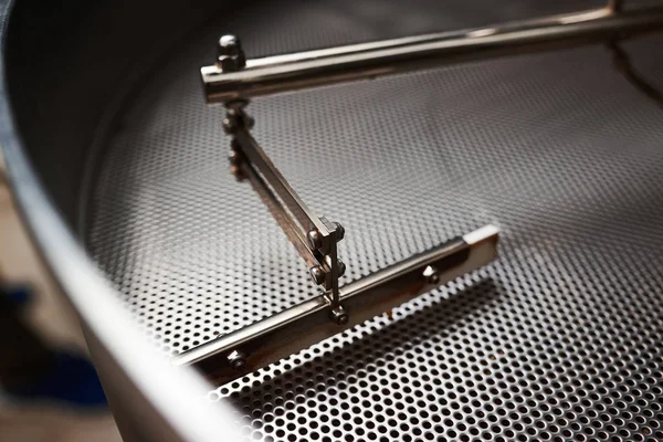 Technology and equipment for processing coffee. Detail of a professional coffee roasting machine. Close-up.