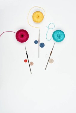 Colorful threads, multi-colored buttons and crochet hooks isolated on white.