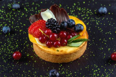 Çikolata, böğürtlen ve şeftali dilimleriyle süslenmiş küçük bir bisküvi. Yakın plan..