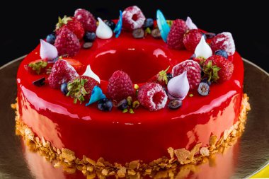 Orijinal tatil pastası güzel bir şekilde kırmızı jöle ve böğürtlenlerle süslenmiş. Siyah arka plan. Yakın plan..