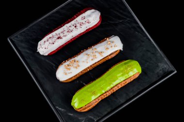 Farklı renklerde güzel ve lezzetli kremalı pastalar. Siyah arka plan. Üst görünüm.