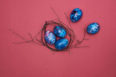 Mutlu Paskalyalar. Dal yuvasındaki Paskalya renkli yumurtalar. Mor arkaplan.