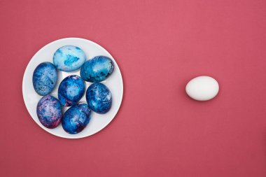 Beyaz tabakta paskalya yumurtası. Mor arka plan. Üst görünüm.