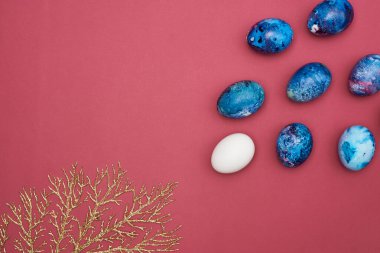 Paskalya bayramı boyalı yumurtalar ve altın bir dal. Burgundy arkaplanı.