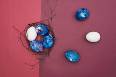 Paskalya yumurtaları ve yuvaları morumsu bir arka planda dallardan geliyor..