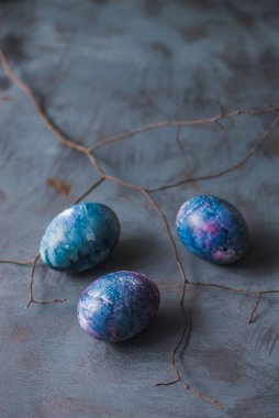 Mutlu Paskalyalar. Mavi arka planda renkli yumurtalar ve dallar..