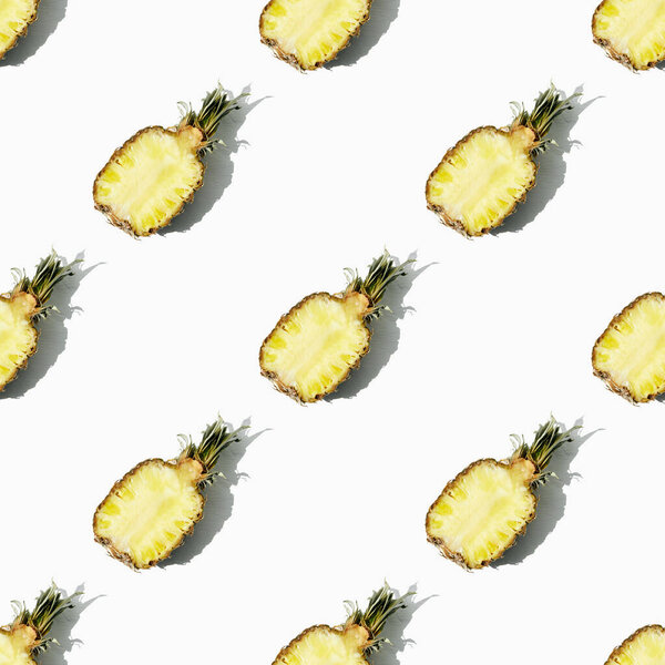 Beautiful bright pattern of halves of ripe juicy pineapple on a white background.