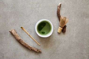 Gri taş yüzeyde organik yeşil kibrit çayı, çay aksesuarları ve tahta çubuklar..
