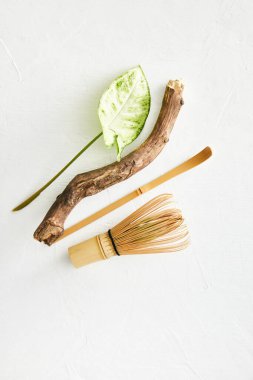 Bambu çırpısı ve bambu kaşığı kibrit çayı, ahşap yemek çubuğu ve beyaz arka planda yaprak..