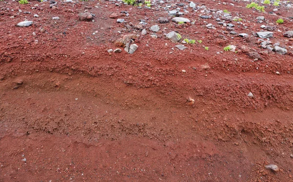 A cut of soil with rocks and red soil — Stock Photo, Image