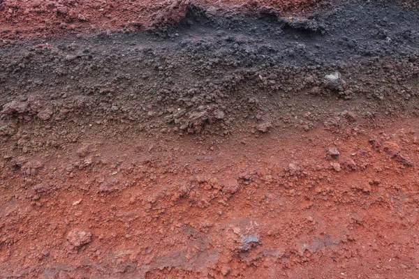 Un corte de tierra con rocas y tierra roja —  Fotos de Stock