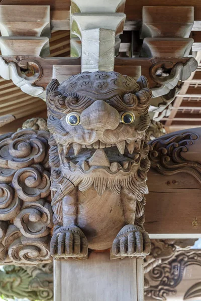 Tallado en madera de un Komainu enojado decora el aguilón de un techo sobre la entrada de un antiguo templo budista en Japón . — Foto de Stock