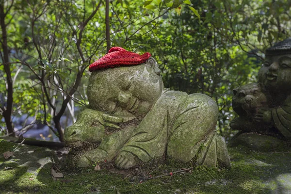 Bull - symbol japonského horoskopu. Dětská kamenná socha Jizo v pletených a plátěných čepicích se zvířetem zvěrokruhu. — Stock fotografie