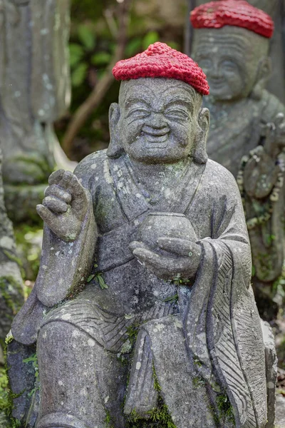 Staré kamenné sochy buddhistických mnichů a jeptišek v pletených a plátěných čepicích — Stock fotografie