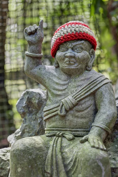 Oude stenen beeld van boeddhistische monnik met gebreide hoed wijzend met de vinger omhoog. — Stockfoto