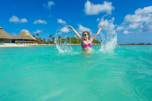 Woman jumping on a back in the beautiful sea. Aruba island — Stock Photo, Image