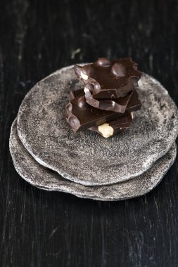 Siyah çikolata parçalarını karanlık bir plaka üzerinde yalan
