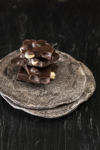 Zwarte chocolade stukjes liggen op een donkere plaat — Stockfoto