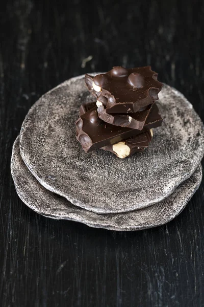 Zwarte chocolade stukjes liggen op een donkere plaat — Stockfoto