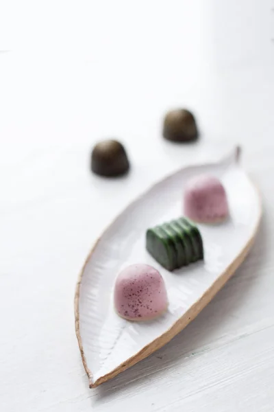 Deliciosos caramelos de chocolate hechos a mano sobre un plato blanco y un fondo blanco — Foto de Stock