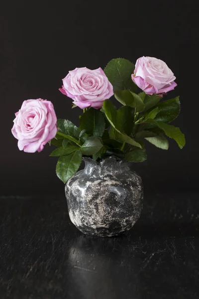 Buquê de rosas rosa em um vaso preto em um fundo preto — Fotografia de Stock