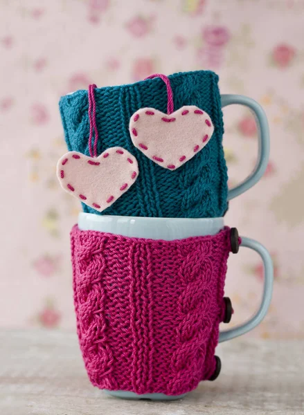 Two blue cups in blue and pink sweater with felt hearts — Stock Photo, Image
