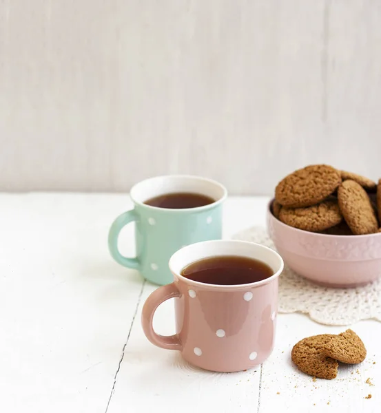 Un tentempié sabroso: dos tazas de té y un tazón de galletas . —  Fotos de Stock