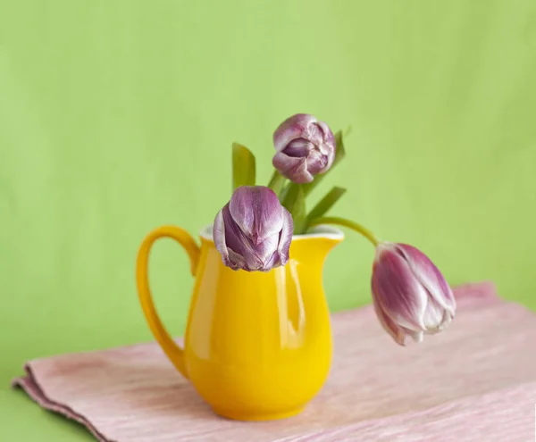 Kytice jemných růžových tulipánů stojí ve žluté váze — Stock fotografie