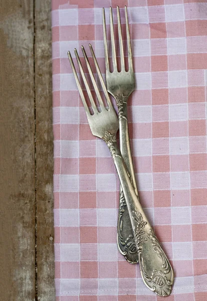 Dos tenedores yacen en una servilleta rosa. La composición se apoya en una madera — Foto de Stock
