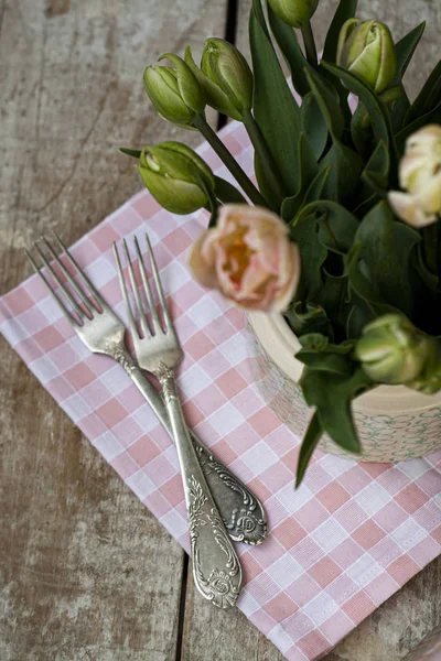 Two forks lie on a pink napkin next to a vase of delicate pink t — Stockfoto