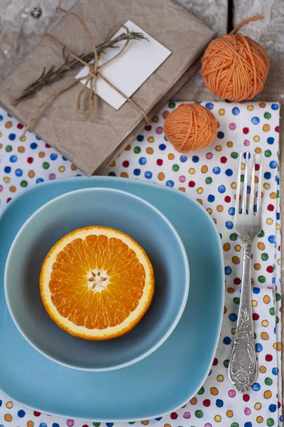 Jasno krojona pomarańcza leży na dwóch niebieskich talerzach. W pobliżu jest widelec, — Zdjęcie stockowe