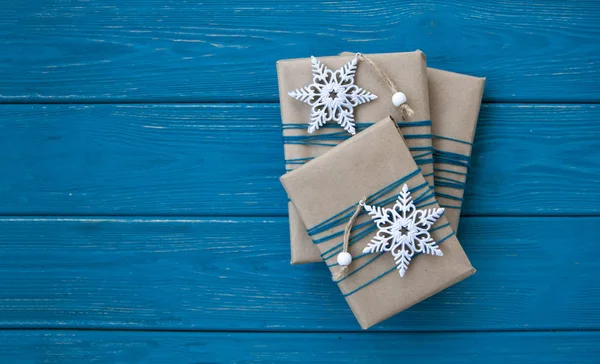 Trzy prezenty zawinięte w papier rzemieślniczy z dwoma białymi orna Boże Narodzenie — Zdjęcie stockowe