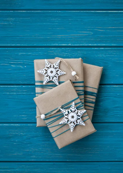 Trois cadeaux enveloppés dans du papier artisanal avec deux ornements de Noël blancs — Photo