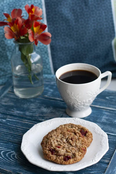 Haferflocken-Kekse, schwarzer Kaffee und ein Strauß roter Blumen — Stockfoto