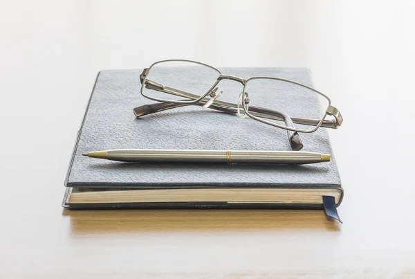 Zwartboek met glazen en pen — Stockfoto