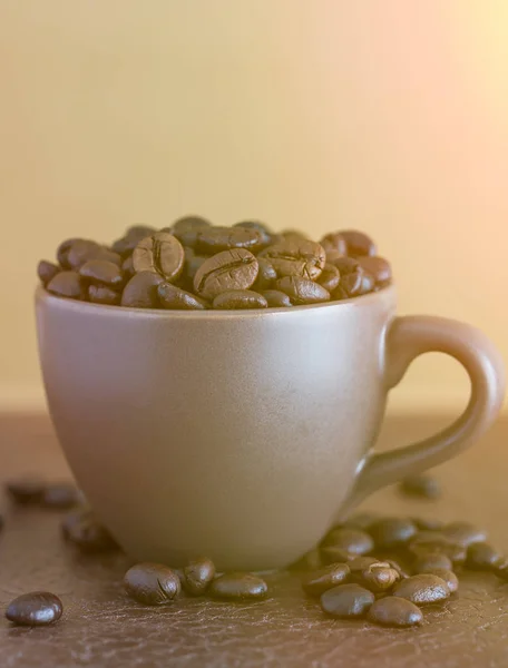 Жареные кофейные зерна в коричневой чашке кофе с солнечным светом — стоковое фото