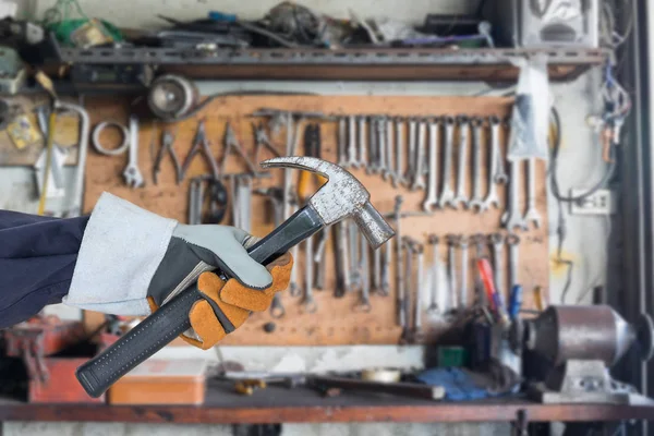 Hand i handske holding hammare med verktyg hängande — Stockfoto